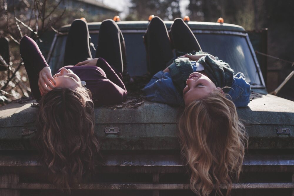 women with long hair chatting on a vintage car